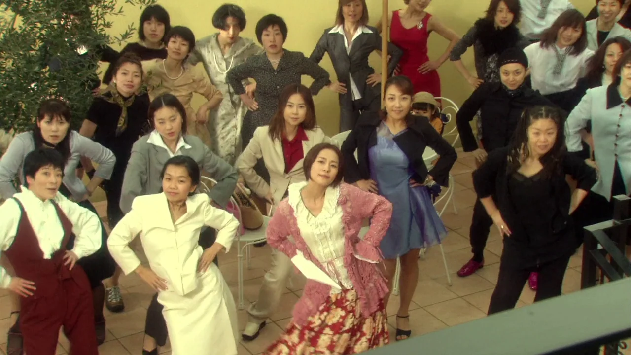 The Happiness of the Katakuris (2001) movie still: wide — A group of women in various business and casual attire pose for a photograph. The…