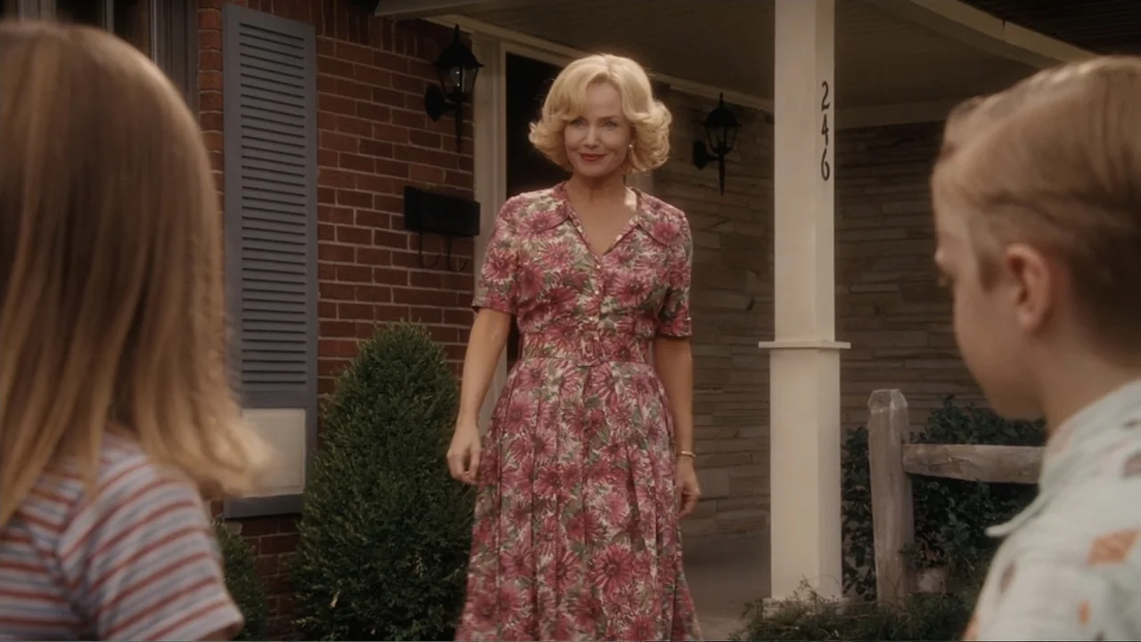 Flipped (2010) movie still: medium — A suburban house porch with brick siding and a white column. A woman in a floral dress stands on the porch…