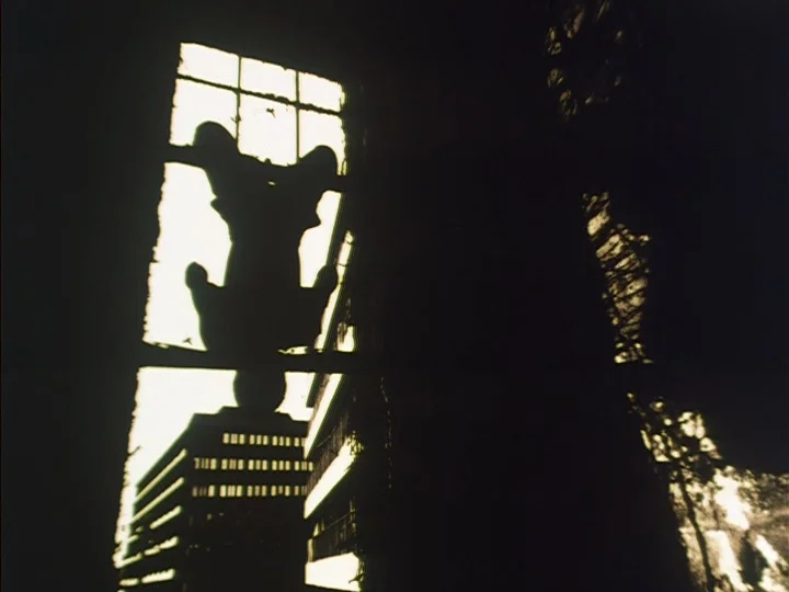 The Reading Machine (1977) movie still: wide — A dark silhouette of a small figure rests against a brightly lit window pane. Outside the window, a…