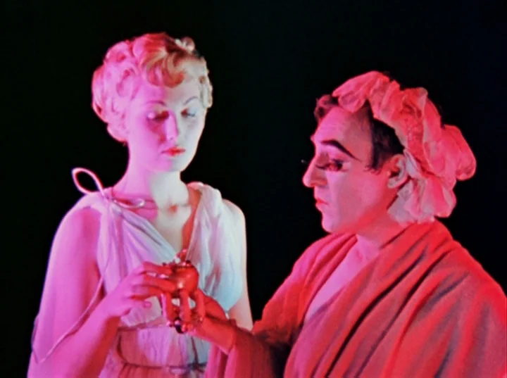 Inauguration of the Pleasure Dome (1954) movie still: medium — A dark stage interior features two performers illuminated by bright magenta lighting.…