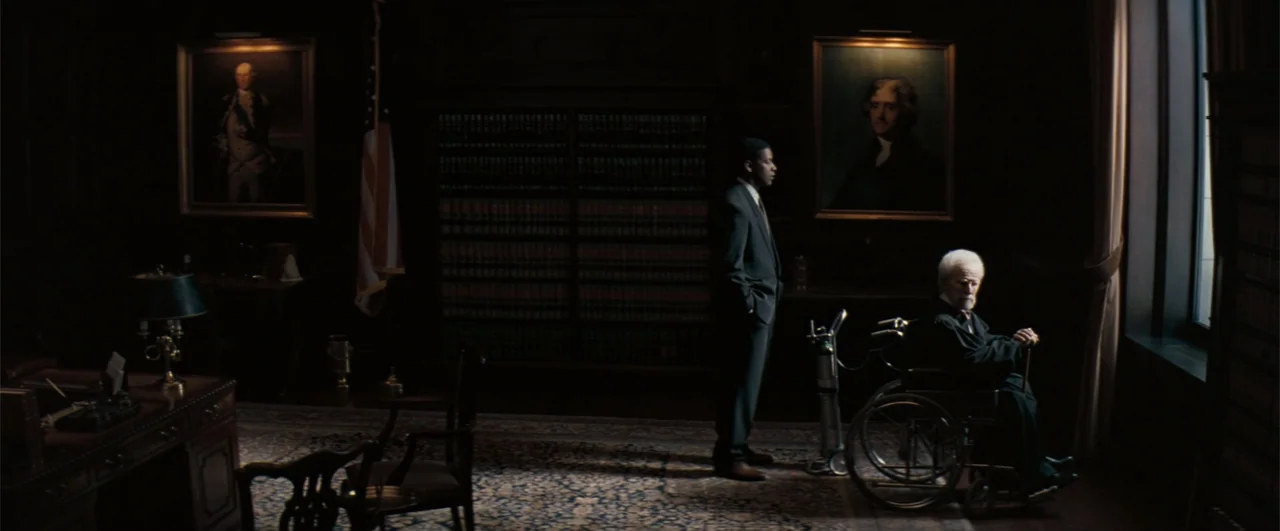 The Pelican Brief (1993) movie still: wide — A dark, wood-paneled law office features two oil paintings on the walls and tall bookshelves. An…