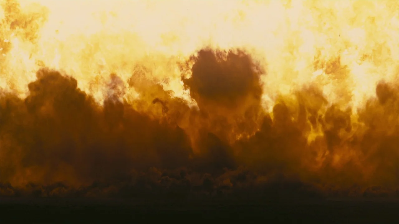 Oppenheimer (2023) movie still: establishing — A dense, expansive wall of dust rises against a flat, horizon-less landscape. The thick particulate…