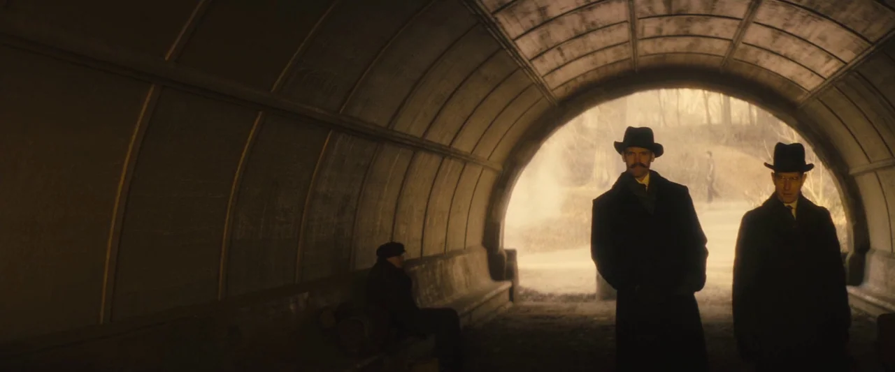 The Immigrant (2013) movie still: wide — A dark concrete tunnel with a curved ceiling and a bench along the side. Three men in vintage suits and…