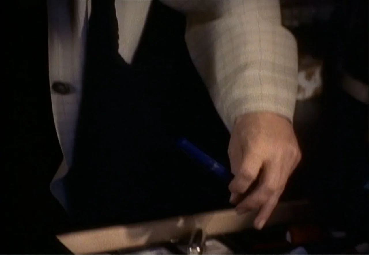 Chance of a Lifetime (1998) movie still: closeup — An interior workspace features a dark desk surface under dim, directional illumination. A…