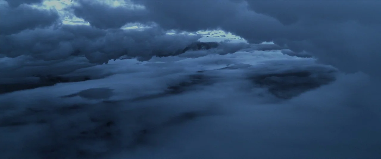 Prometheus (2012) movie still: establishing — A view from high altitude looking down at dense layers of thick clouds. The dark sky is illuminated by…