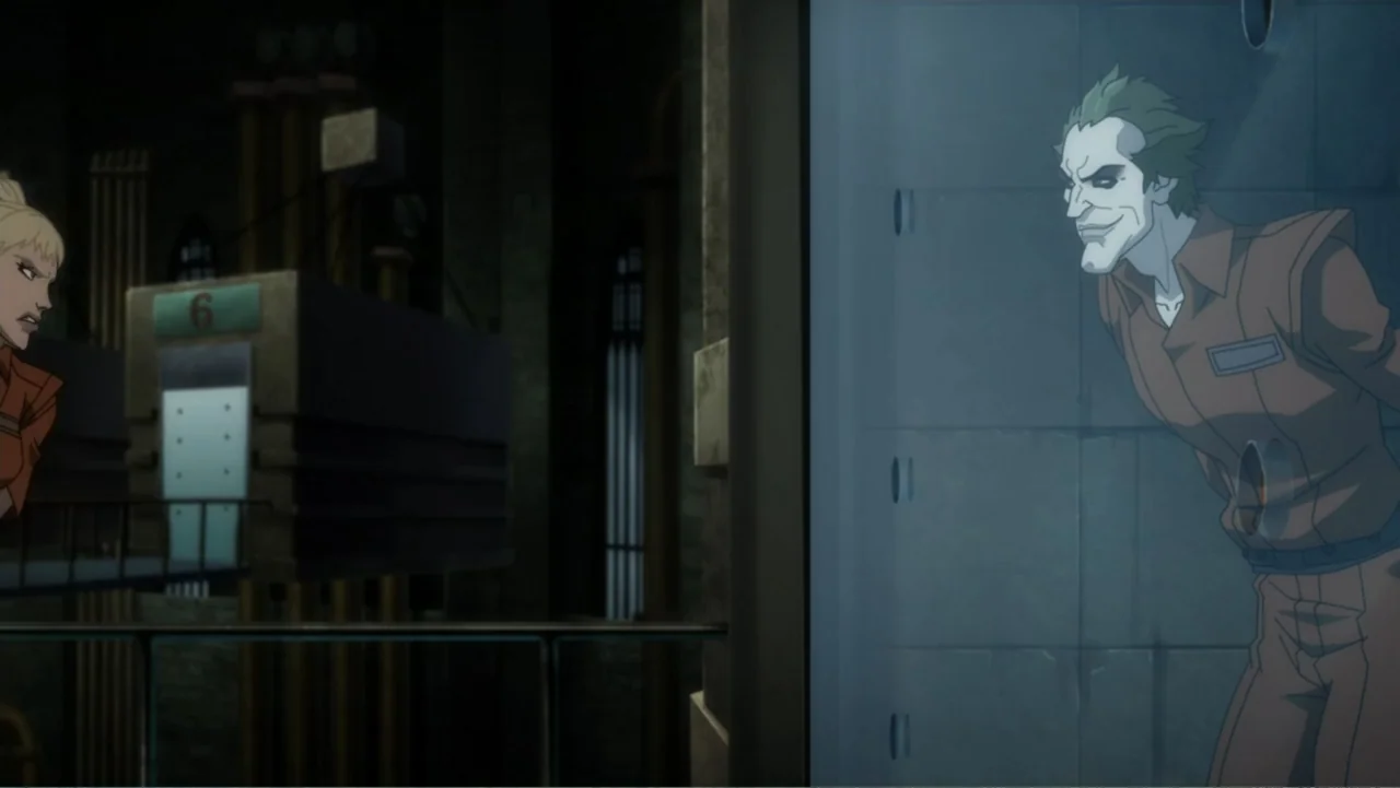 Batman: Assault on Arkham (2014) movie still: medium — A dark prison visitor area features industrial walls and a glass security partition. A man in…
