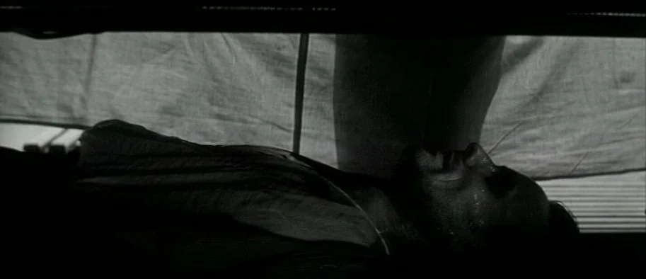 And The Fifth Horseman is Fear (1965) movie still: closeup — A man lies on a bed in a darkened room, face turned toward a window. A white sheet…