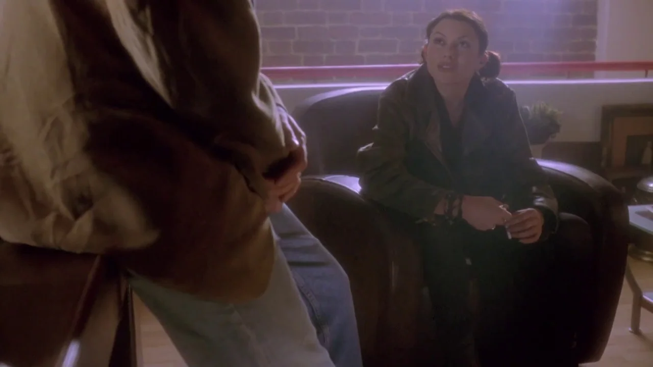 Hellraiser: Deader (2005) movie still: medium — A loft space with an exposed brick wall and a large window background. A woman sits in a leather…