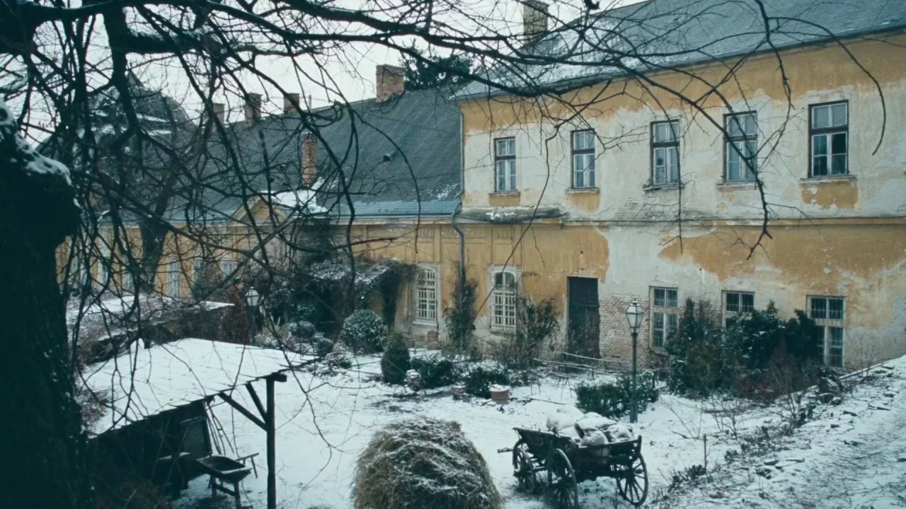 Childhood of a Leader (2015) movie still: establishing — A snow-covered courtyard sits before a dilapidated yellow building with weathered plaster…