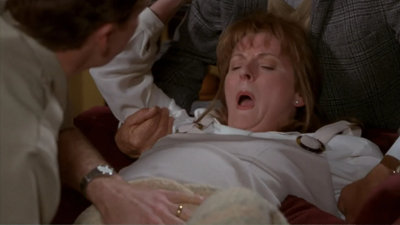 Music from Another Room (1998) movie still: medium — A domestic bedroom environment with neutral bedding and soft overhead lighting. A woman lies on…