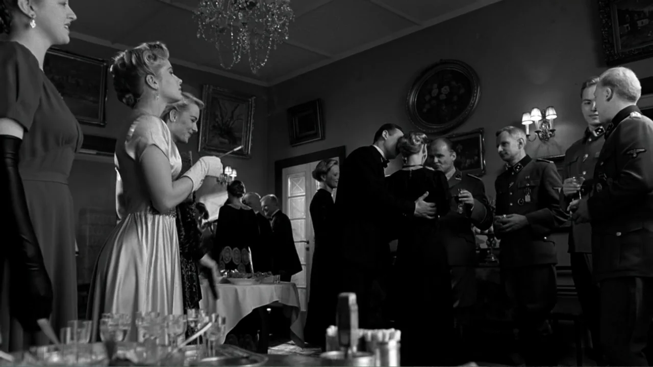 Schindler's List (1993) movie still: medium — A formal interior space contains multiple guests gathered around a laden table for dinner. Men in…