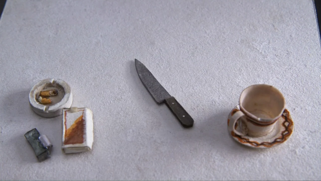 Bestia (2017) movie still: wide — A miniature tabletop display features a knife, cigarette butts, and a coffee cup. These items are arranged neatly…