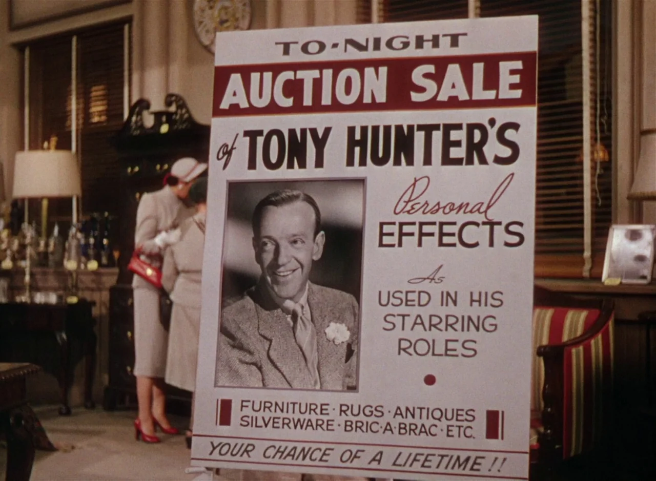 The Band Wagon (1953) movie still: medium — An interior space displays a large promotional sign advertising the personal effects of Tony Hunter. In…