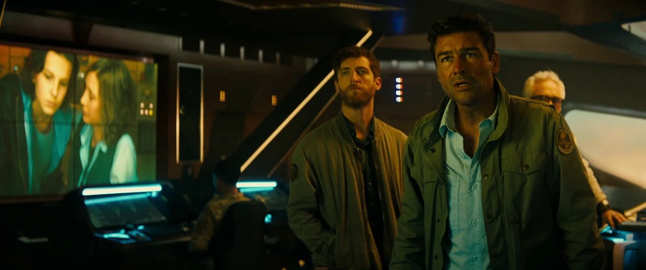 Godzilla: King of the Monsters (2019) movie still: medium — A high-tech command center features large wall-mounted screens displaying video feeds.…