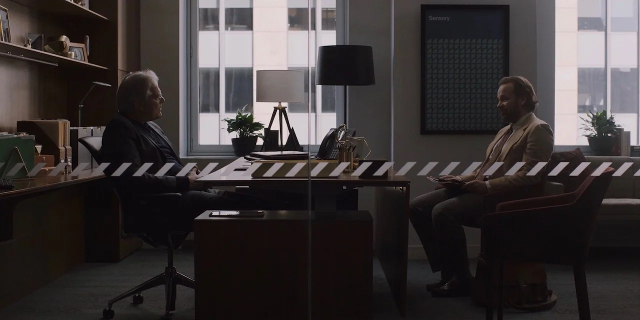The Sound of Silence movie still: wide — A modern professional office with a desk placed between two large windows. An older man and a middle-aged…