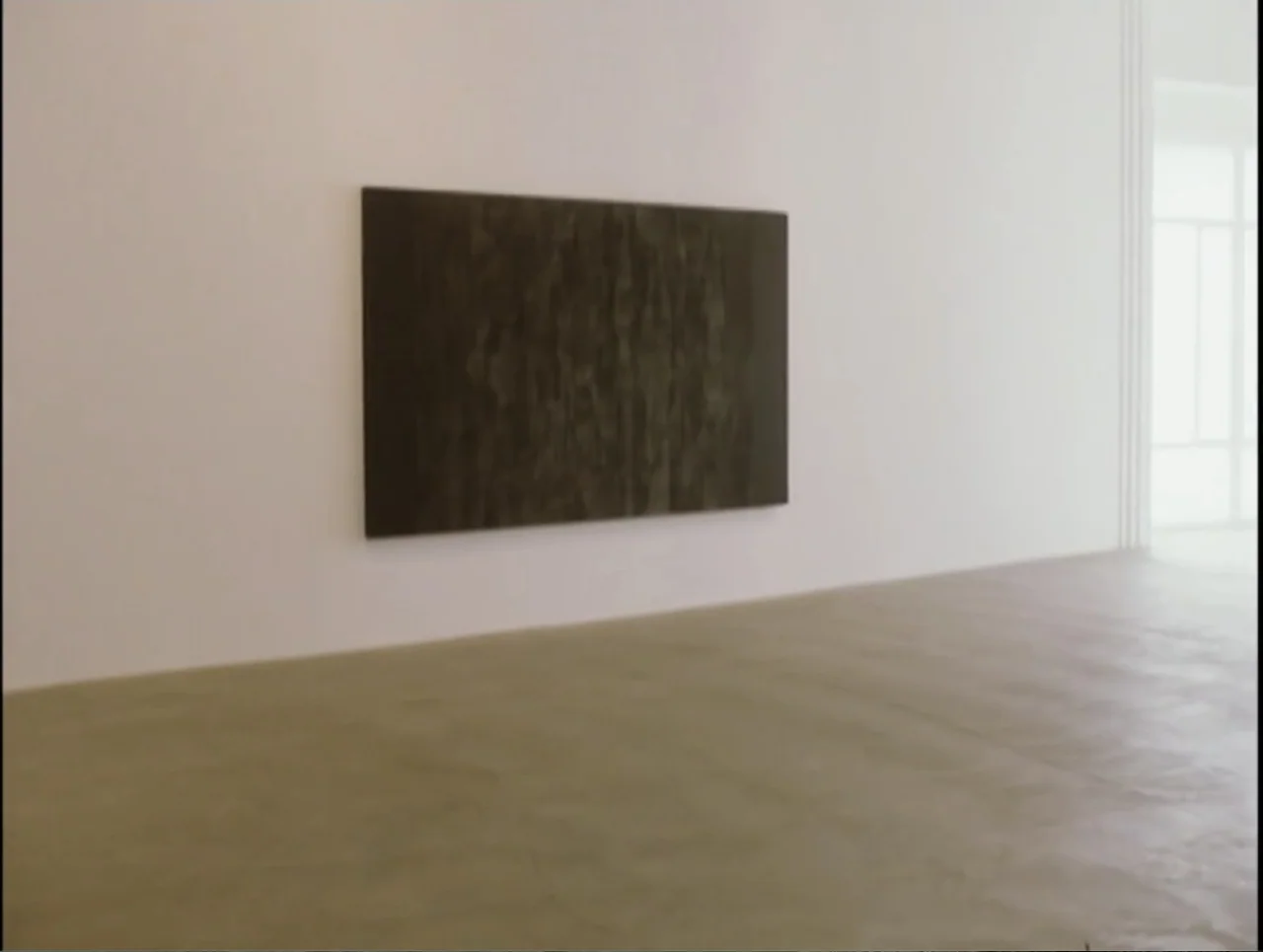 Apartment 12 (2001) movie still: wide — A minimalist white-walled room contains a single rectangular dark painting on the wall. The space is…