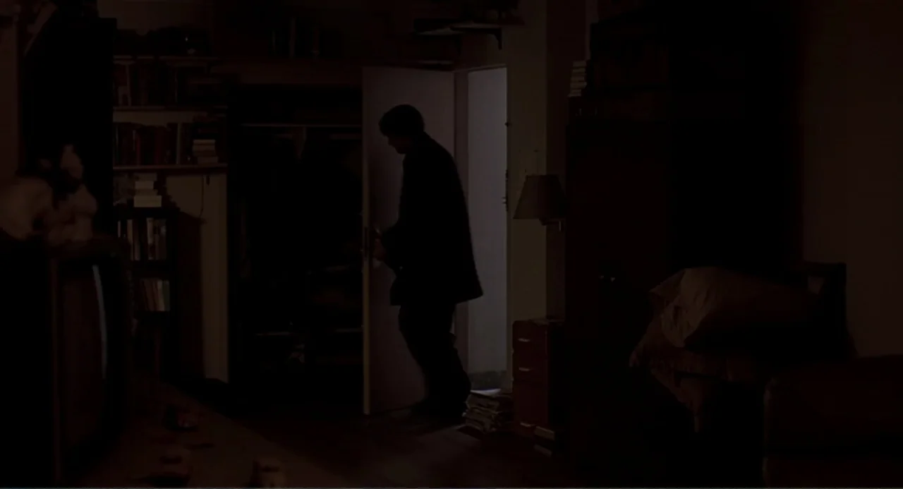 Eternal Sunshine of the Spotless Mind (2004) movie still: medium — A dark bedroom contains shelves of books, a television, and a stack of papers. A…
