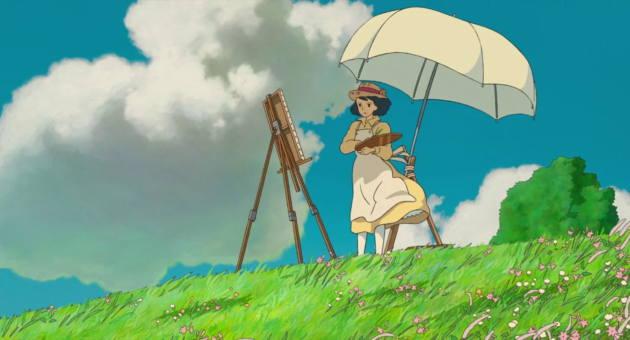 The Wind Rises (2013) movie still: fullbody — A grassy hillside with wild flowers under a bright blue sky with white clouds. A young woman stands at…