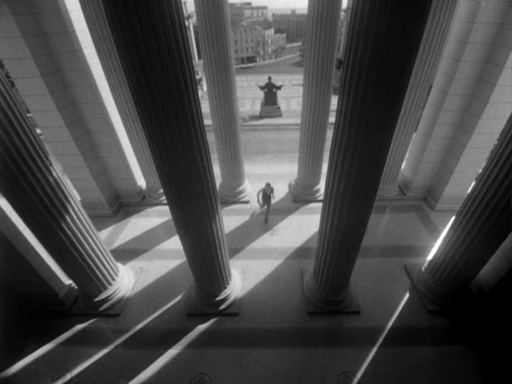 I Am Cuba (1964) movie still: wide — A stone plaza is surrounded by massive neoclassical columns casting long, geometric shadows. A man runs across…