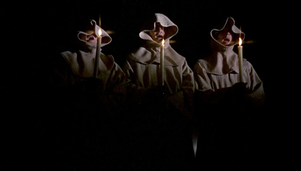 Head (1968) movie still: medium — Three individuals wearing monk robes with hoods stand against an entirely black void. Each person holds a single…