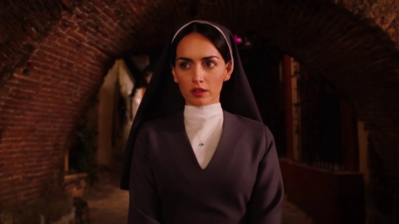 Nacho Libre (2006) movie still: medium — A woman dressed as a nun stands under a dark brick arched passage. She stares forward while the background…