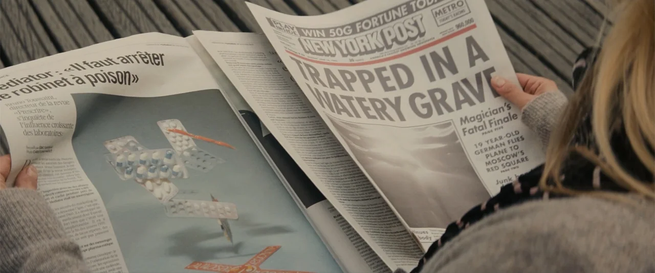 Now You See Me (2013) movie still: closeup — A close-up view shows a person holding a newspaper open in their hands. The newspaper features a…