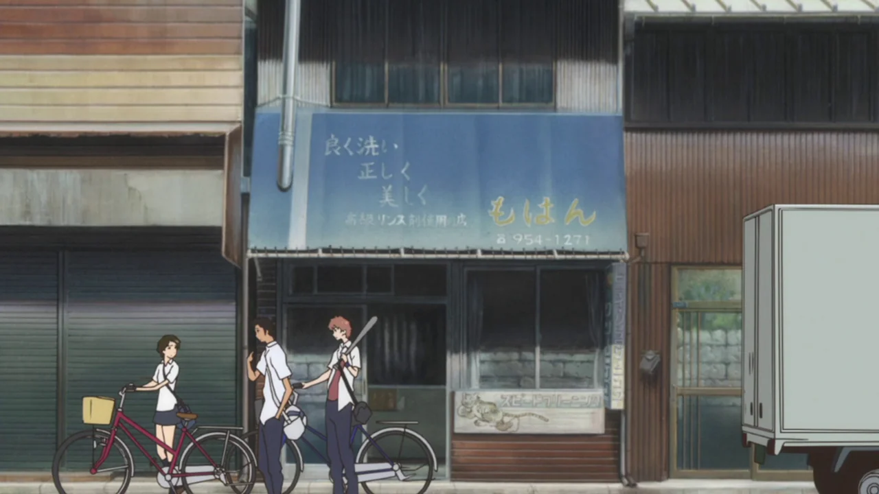 The Girl Who Leapt Through Time (2006) movie still: fullbody — A Japanese storefront with a faded blue awning and a hand-painted sign sits curbside.…