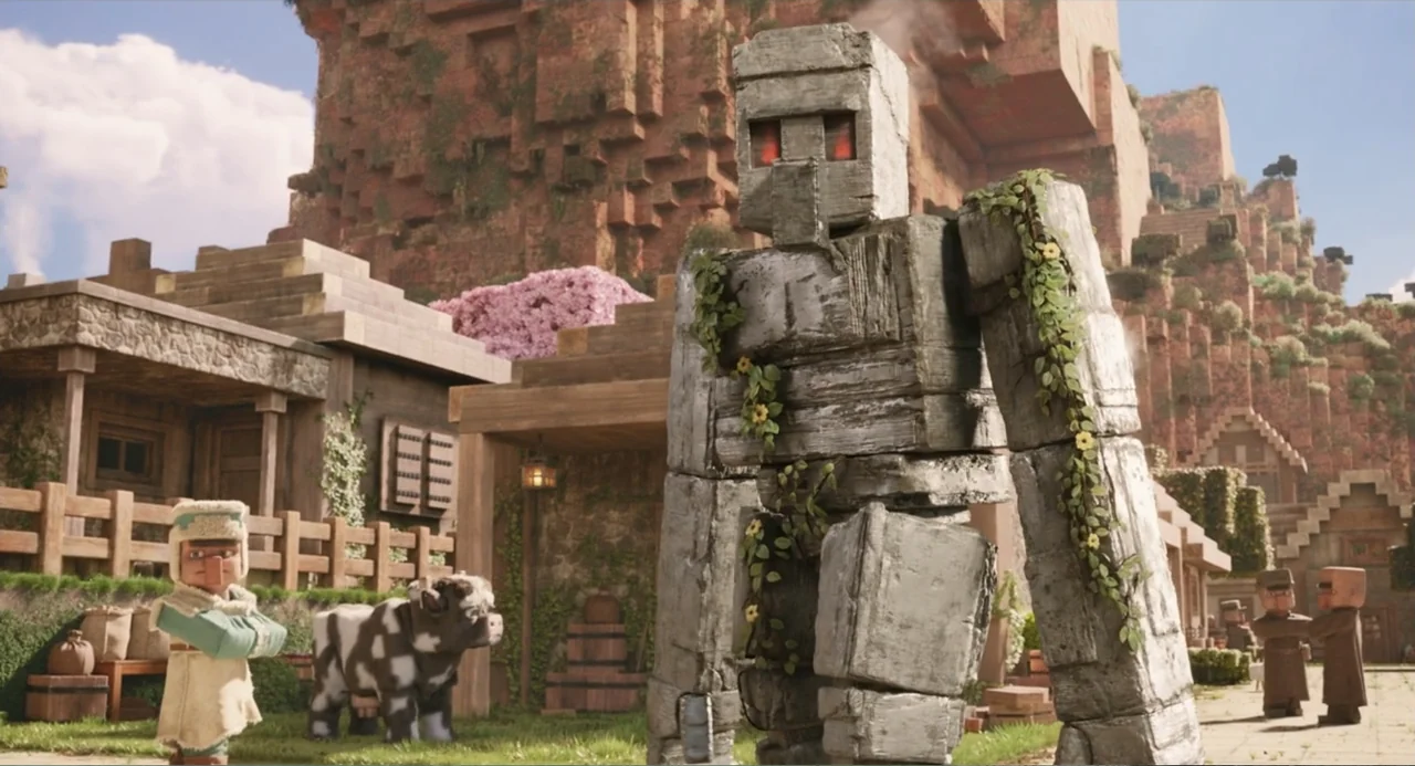A Minecraft Movie (2025) movie still: medium — A blocky stone golem stands in the center of a pixelated village square. A villager stands on the…