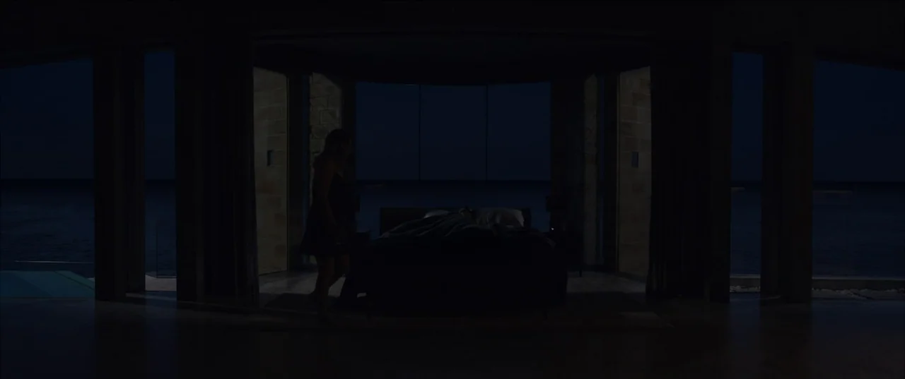 The Invisible Man (2020) (2020) movie still: wide — A dark, modern coastal bedroom features floor-to-ceiling windows overlooking a nighttime ocean…