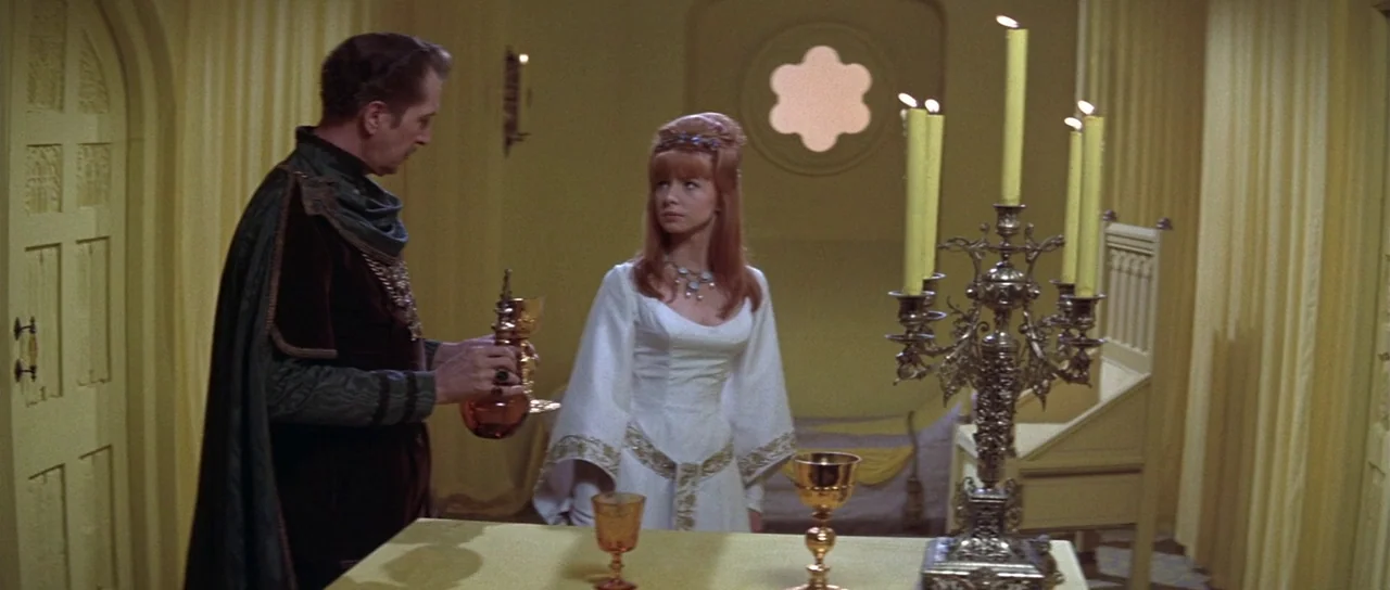 The Masque of the Red Death (1964) movie still: medium — A medieval chamber features yellow curtains and a small circular window with stone tracery.…