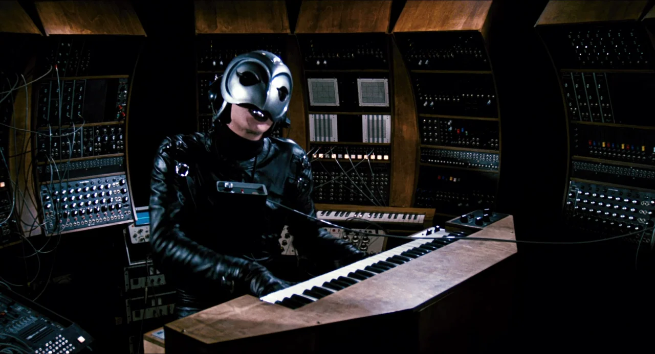 Phantom of the Paradise (1974) movie still: medium — A dark space filled with curved wooden panels housing vintage analog synthesizers and modular…
