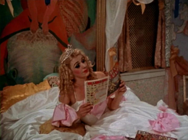 Desperate Living (1977) movie still: medium — A bedroom features a wall decorated with a large colorful artistic mural. A woman wearing a tiara…