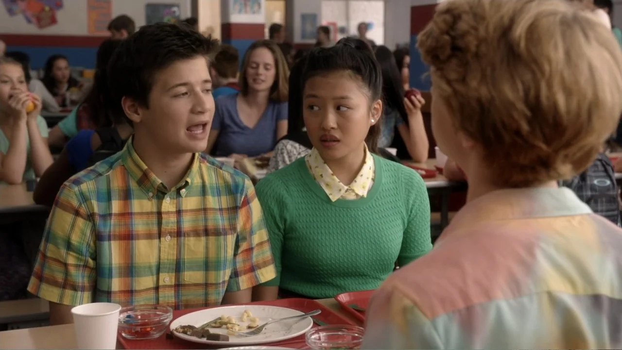Rufus 2 (2017) movie still: medium — A crowded school cafeteria with long tables and rows of students eating lunch. Three students sit at a table…