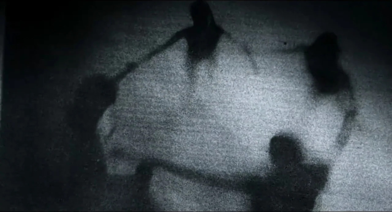 The Ring Two (2005) movie still: wide — A grainy high contrast view shows four dark silhouettes against a bright surface. The figures stand in a…