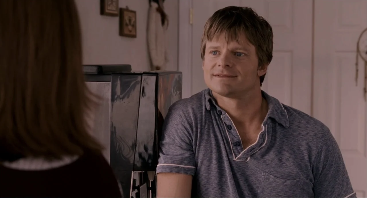 Management (2009) movie still: medium — A light-colored kitchen interior features a coffee machine on the counter. A man stands in the foreground…