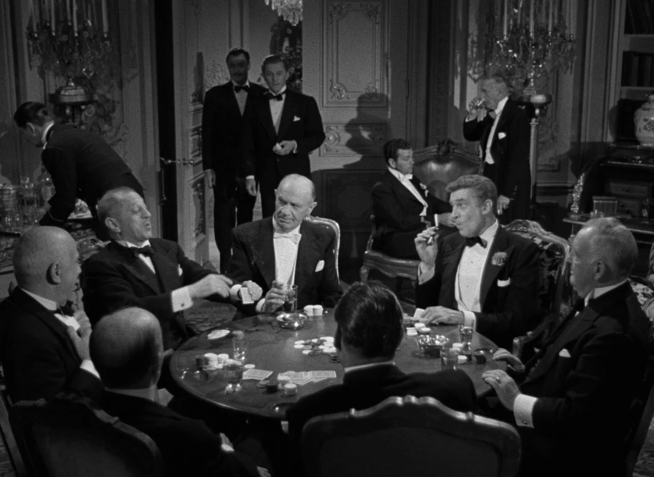 The Bad and the Beautiful (1952) movie still: medium — A group of men in tuxedos sit around a circular table in an ornate room. They play a card…
