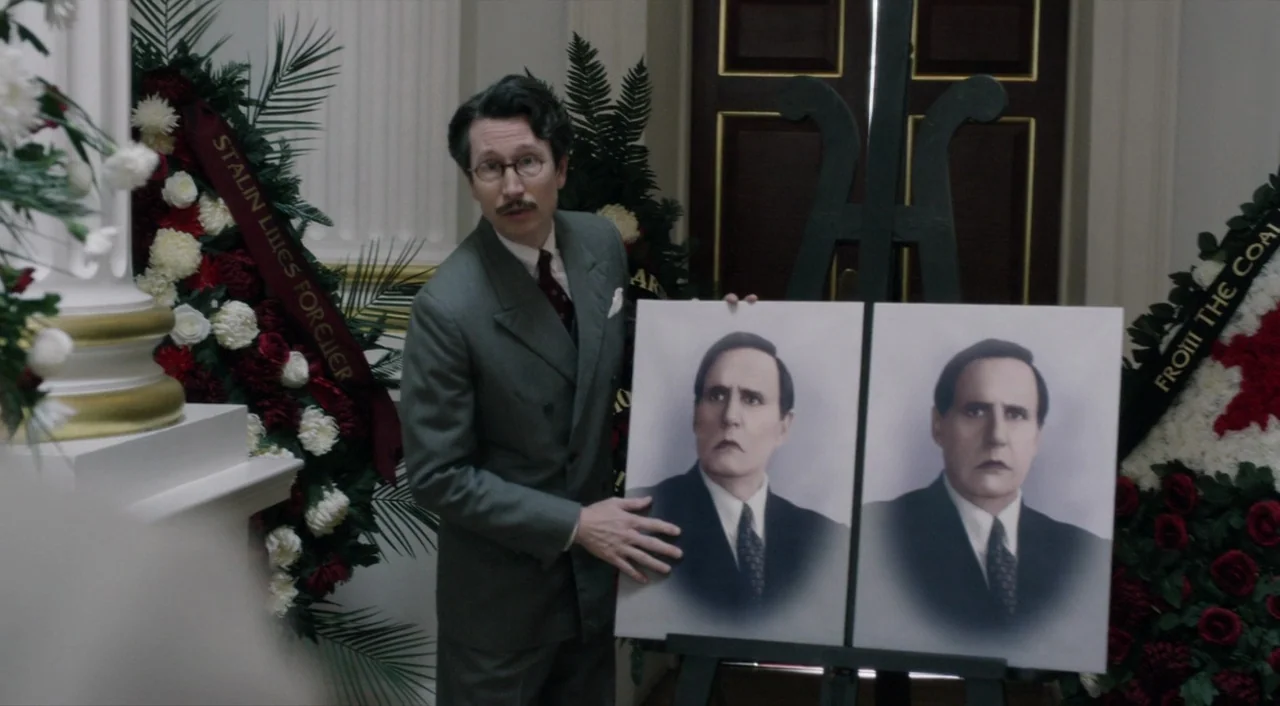 The Death of Stalin (2017) movie still: medium — An interior space decorated with large floral funeral wreaths containing red and white flowers. A…