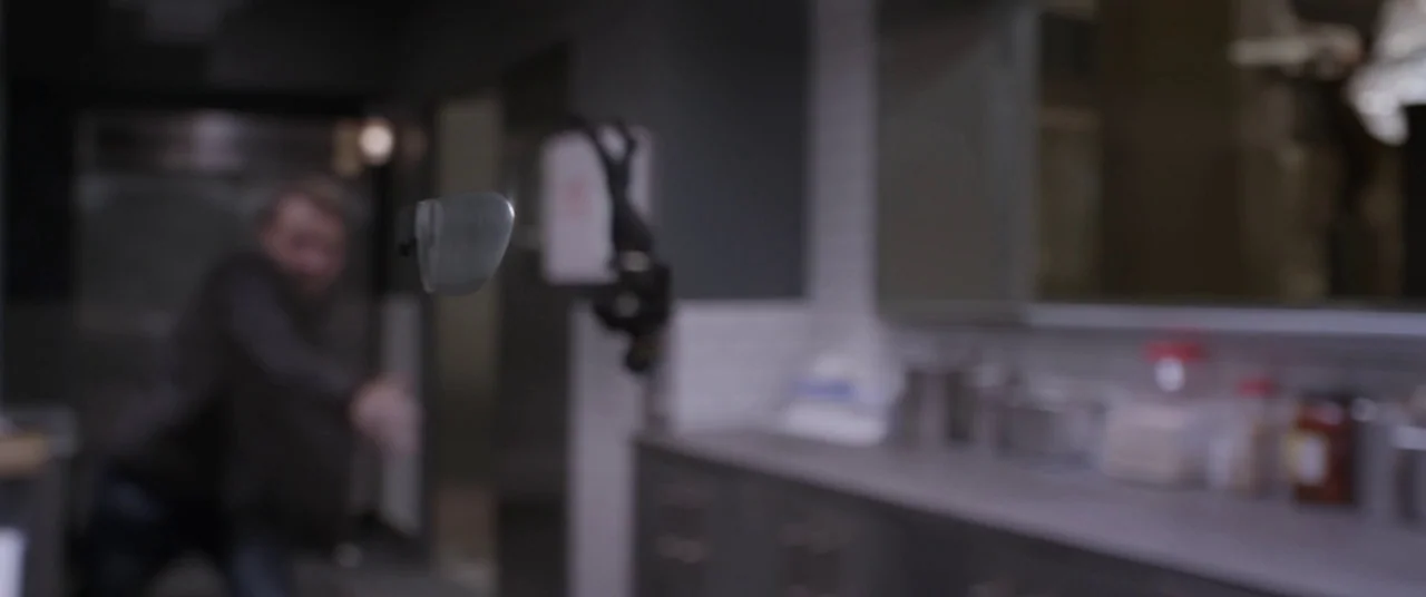 Ant-Man and the Wasp (2018) movie still: closeup — A dark indoor setting features a blurred kitchen counter and walls in the background. A pair of…