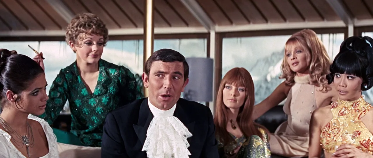 On Her Majesty’s Secret Service (1969) movie still: medium — A bright room with floor to ceiling windows showing snowy mountains in the background.…