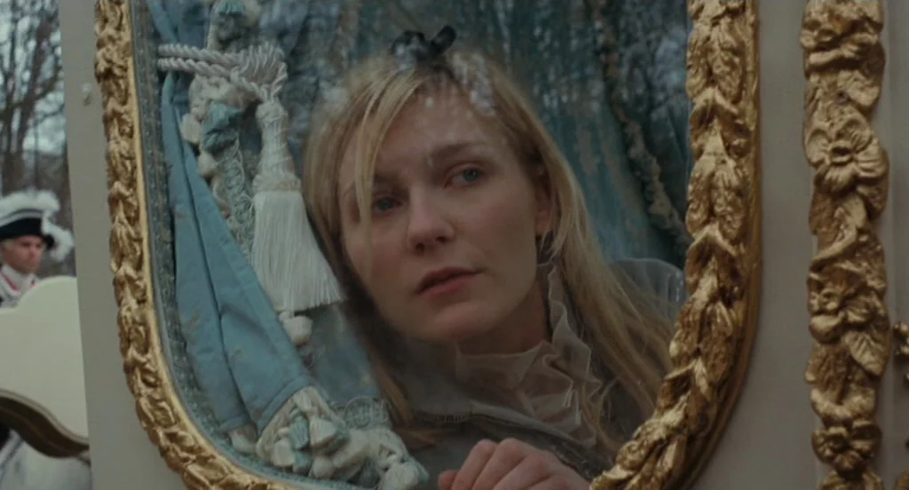 Marie Antoinette (2006) movie still: closeup — The interior of an ornate 18th-century carriage with gold-trimmed edges and blue upholstery. A young…