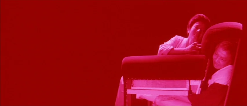 The Horrors of Malformed Men (1969) movie still: medium — A minimalist set is entirely bathed in a uniform, high-intensity red color wash. An Asian…