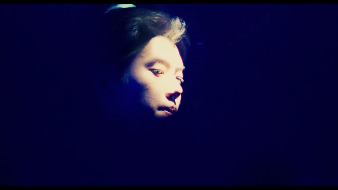 Millennium Mambo (2001) movie still: closeup — A dark space with a person illuminated by a bright, focused beam of light. The subject is partially…