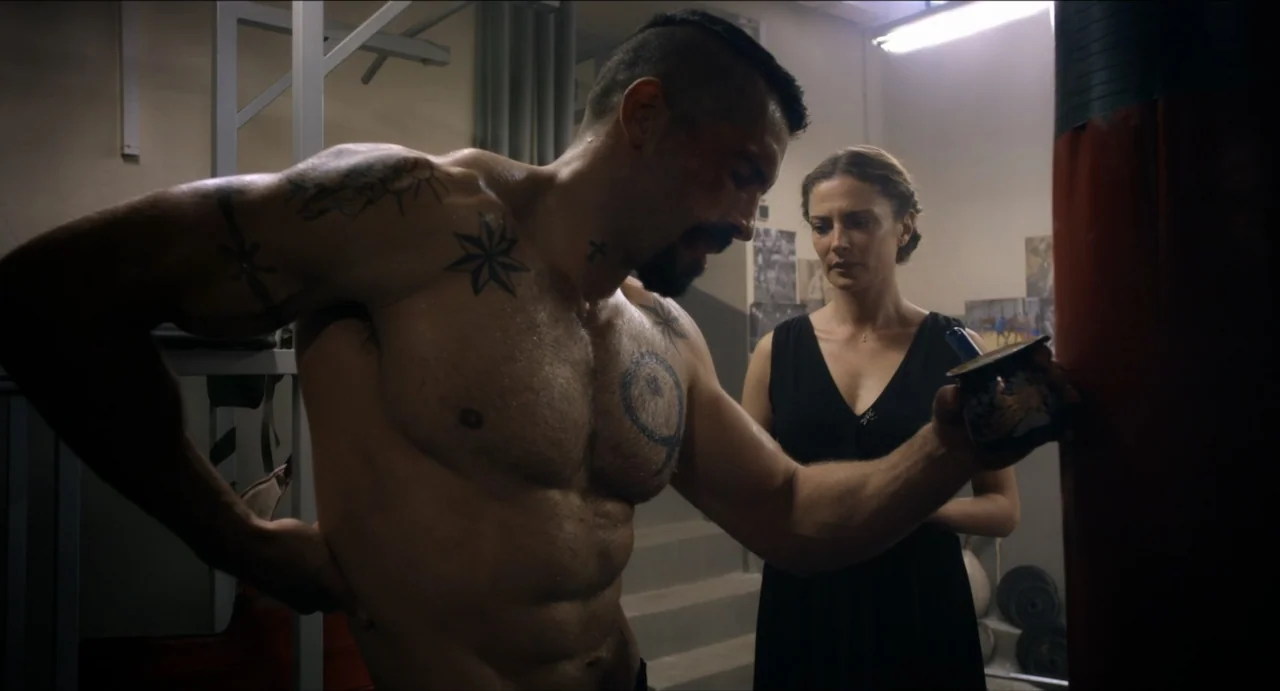 Boyka: Undisputed IV (2016) movie still: medium — An interior space features athletic training equipment and muted grey walls. A muscular shirtless…