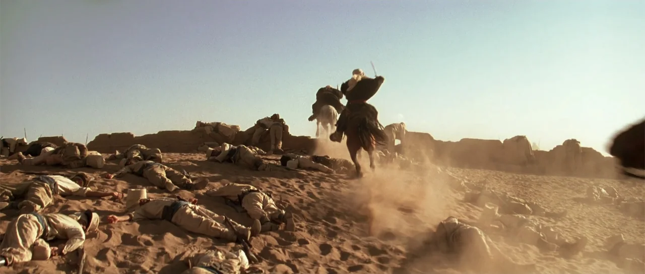 The Mummy (1999) movie still: wide — A vast sandy battlefield strewn with bodies lies under a clear, bright desert sky. A lone soldier on horseback…