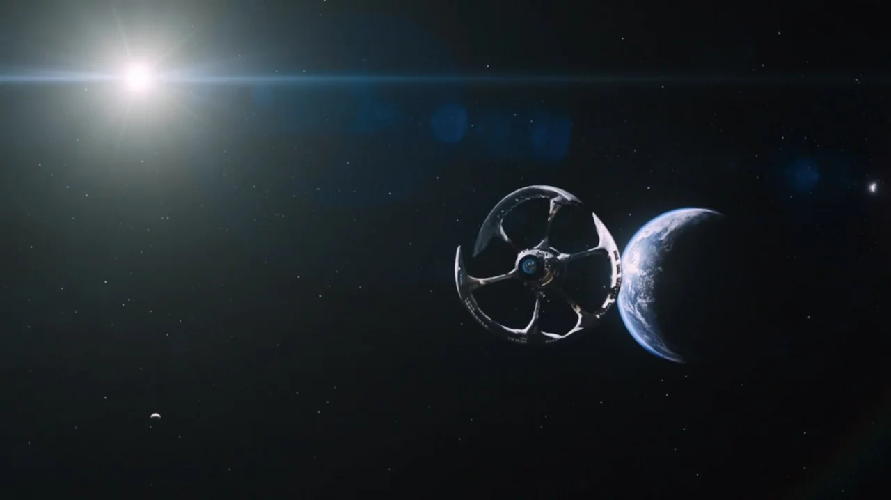 Passengers (2016) movie still: establishing — A large circular space station floats in the dark expanse of space near Earth. The bright light of a…