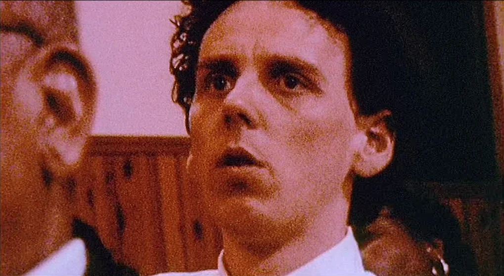 Julien Donkey Boy (1999) movie still: closeup — A close-up shot focuses on a young man in a room with wood paneling. The man stares forward with his…