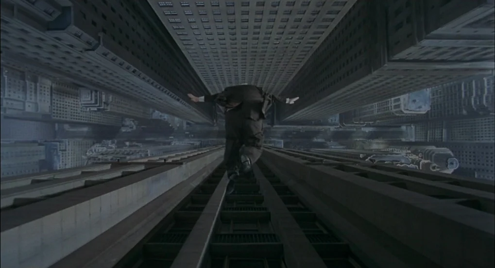 The Hudsucker Proxy (1994) movie still: fullbody — Two monolithic skyscrapers flank a void where a man falls through empty space. The architecture…