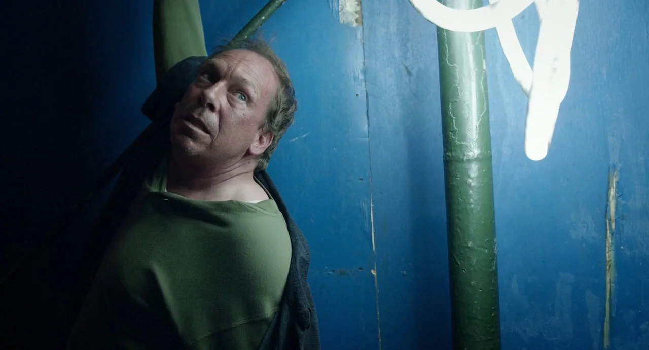 Birdman (2014) movie still: medium — An interior space with bright blue painted walls and a single thick green pillar. A middle-aged man reaches…