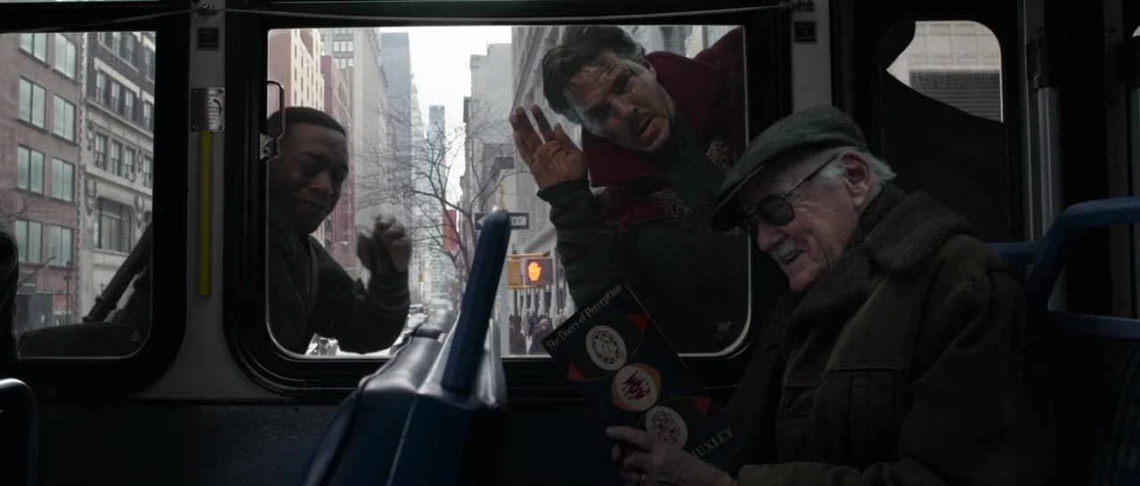 Doctor Strange (2016) movie still: medium — Inside a public transit bus with a passenger reading a book by the window. Outside the bus, two men in…