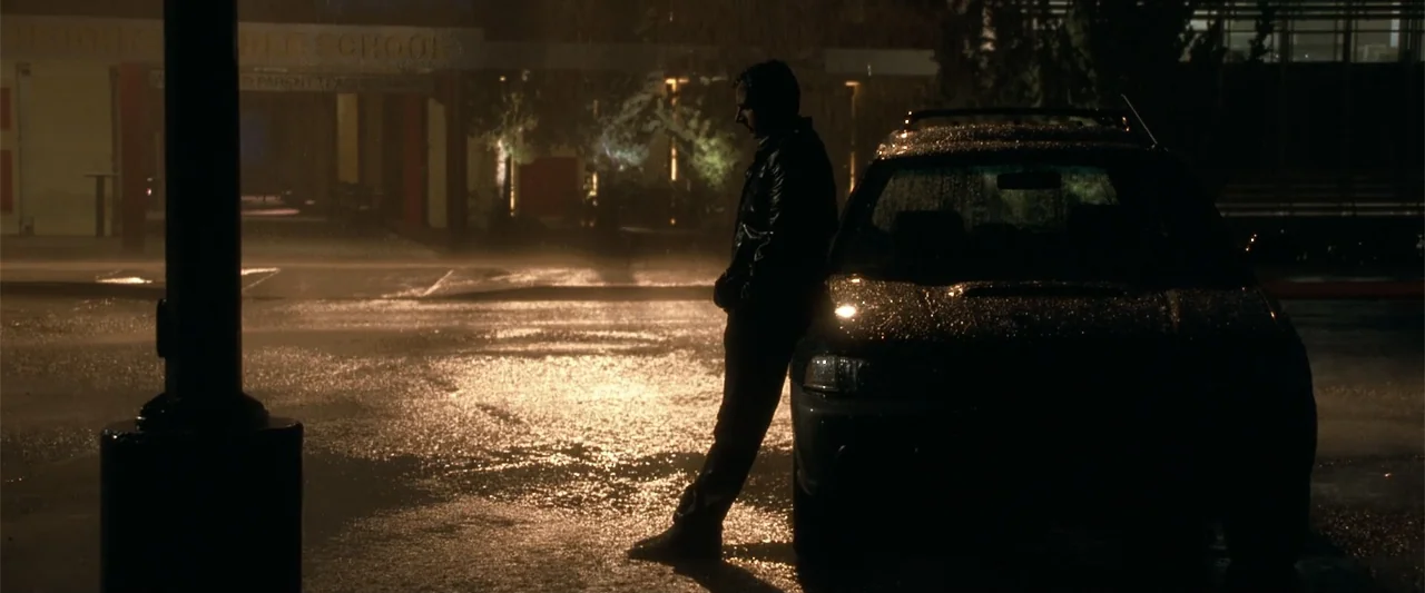 Crazy, Stupid, Love. (2011) movie still: fullbody — A wet asphalt lot at night is illuminated by the harsh overhead street lighting. A solitary man…